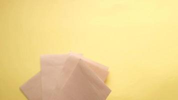 Lined paper sheets fall on yellow table top in slow motion video