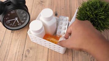 Container of pills and clock on table video