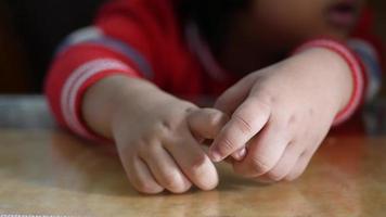 Seated child rubs hands together at table video