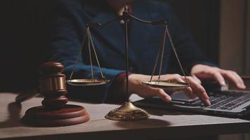 Justice and law concept.Male judge in a courtroom with the gavel, working with, computer and docking keyboard, eyeglasses, on table in morning light video