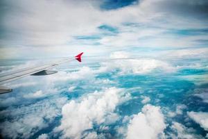 Wing of an airplane flying above white clouds. photo