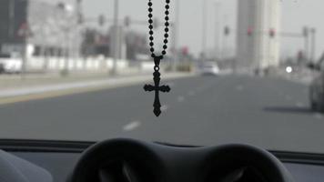 Die Halskette mit dem christlichen Kreuz hängt in der Windschutzscheibe des fahrenden Autos video