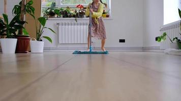 een meisje dansen met een dweilen naar schoon de verdieping in een nieuw huis - algemeen schoonmaak in een leeg kamer, de vreugde van in beweging, helpen met de huiswerk video