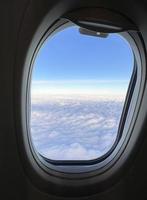 View from the airplane window. Beautiful cloudscape with blue sky. Wonderful panorama above white clouds as seen through window of an plane. Traveling by air concept photo