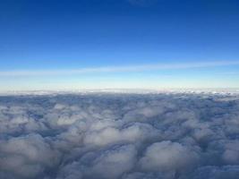 View from the airplane window. Beautiful cloudscape with blue sky. Wonderful panorama above white clouds as seen through window of an plane. Traveling by air concept photo