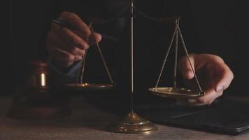 Business and lawyers discussing contract papers with brass scale on desk in office. Law, legal services, advice, justice and law concept picture with film grain effect video