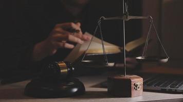 Business and lawyers discussing contract papers with brass scale on desk in office. Law, legal services, advice, justice and law concept picture with film grain effect video