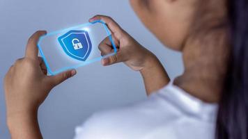 Woman holding phone tablet screen with protection icon. Represents protection against external hacks. Security concepts against code, virus, firmware and malware. photo