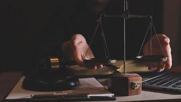 Business and lawyers discussing contract papers with brass scale on desk in office. Law, legal services, advice, justice and law concept picture with film grain effect video