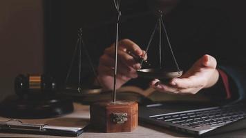 Business and lawyers discussing contract papers with brass scale on desk in office. Law, legal services, advice, justice and law concept picture with film grain effect video