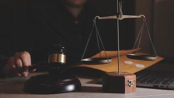 Business and lawyers discussing contract papers with brass scale on desk in office. Law, legal services, advice, justice and law concept picture with film grain effect video