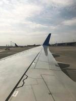 Wing of a beautiful fast jet airplane with an engine on the runway at the airport. Vertical photo