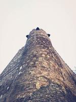 Beautiful vintage ancient old stone medieval authentic high protective tower of cobblestones against a blue sky photo