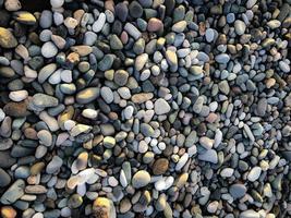 Texture of many multicolored beautiful round and oval smooth natural stones, pebbles. The background photo