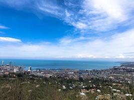 la vista desde lo alto de una hermosa ciudad turística con edificios y casas, techos de árboles y plantas, naturaleza contra un cielo azul y montañas. arquitectura antigua europea foto