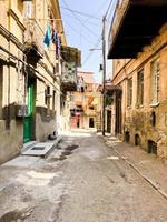 Narrow street, lane, tunnel with old houses, buildings on the sides in a poor area of the city, slums. Vertical photo