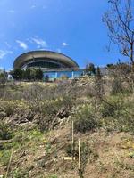 Unusual futuristic round building in the form of a flying saucer on top of a green hill with grass and bushes photo