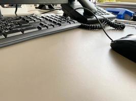 Black modern computer mouse keyboard and telephone on a working office table in a business company photo