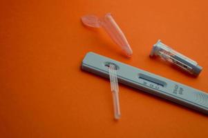 test for coronavirus on an orange background. on a matte background, a sensitive strip for coronavirus, a lancet, a container for a physical solution. home test kit for coronavirus photo