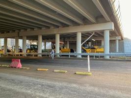 trabajo industrial de construcción bajo el puente y el gran paso elevado de la autopista con la ayuda de modernos equipos de construcción como rodillos de asfalto foto