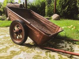 a metal wheelbarrow with large wheels stands on a carpet. garden care in russia. carpet on the street, fashion from the 90s. stylish and fashionable interior, wealth photo