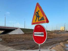 bajo el letrero del tablero de construcción en la carretera cerrada con señal de flecha y cono de tráfico. símbolo de precaución en construcción, signo de trabajo en progreso foto