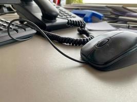 Black landline telephone with a tube, buttons and a wire on the work table at the office desk with office supplies. Business work photo