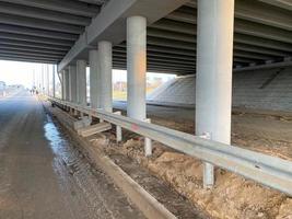 Construction industrial work under a bridge with columns and bumpers and a large car overpass road photo