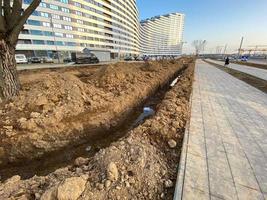 An excavated pit is a ditch for laying cables and wires with pipes under the ground during the construction and repair of houses in the city of the megalopolis photo