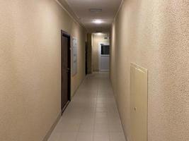 Long narrow yellow beige corridor with apartments in a new modern building photo