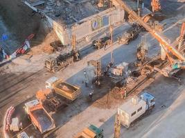 construction of a new overpass in the city center on a snowy street. road repair, yellow dump trucks carry asphalt, sand for paving photo