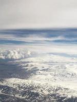 View from above, from a great height to high mountains with snow with snowy peaks and clouds photo