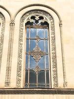 Beautiful vintage ancient old carved window with glass with a forged frame arches and patterns. The background photo