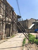 Iron pillars, piles propped up, keep leaning down falling old dangerous dilapidated collapsing house building. Unusual funny architecture photo