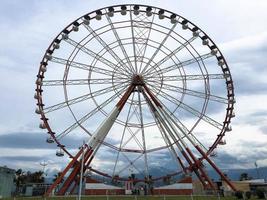 A large round beautiful Ferris wheel, a panoramic platform in a park on a tropical sea warm summer resort with palm trees against a blue sky photo