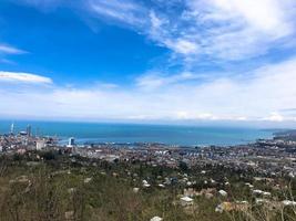 la vista desde lo alto de una hermosa ciudad turística con edificios y casas, techos de árboles y plantas, naturaleza contra un cielo azul y montañas. arquitectura antigua europea foto