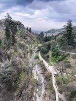 vista superior de las hermosas montañas y colinas con bosques y árboles y senderos de montaña, caminos con puentes contra el cielo azul foto