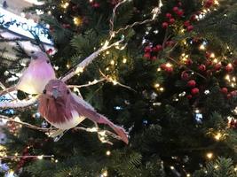 Christmas tree decoration. Toy bird sits om a branch tree in a fairy forest on blurred Christmas background. The concept of New Year and Christmas. Festive decoration photo