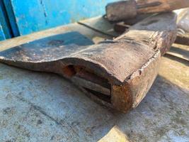 An old iron metal ax with a butt and a rusty and texture beautiful handle for chopping firewood, wood and trees lies on an iron background photo