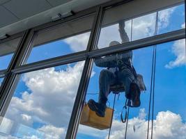 Industrial climber washes the facade glazing in rubber gloves. Protection from the coronavirus pandemic. Surface photo