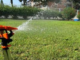 Automatic green grass sprinkler, water sprayer for watering lawn plants photo