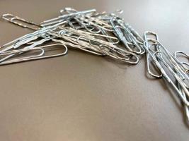 Shiny metal paper clips on a desktop with stationery in a business office. Close view photo