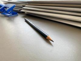 A simple black pencil lies sharply sharpened next to folders with sheets of paper and documents on the working business desk in the office. Stationery photo