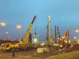 construction of a bridge in the city center. construction of a new overpass from concrete blocks. a heavy, yellow crane carries huge blocks to a construction site photo