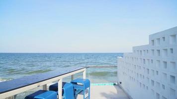 desk and bar stool near swimming pool with sea and sky background video