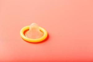 Opened condom on a pink background, close-up, top view. photo