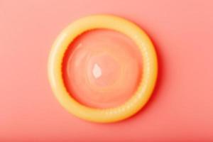 Opened condom on a pink background, close-up, top view. photo