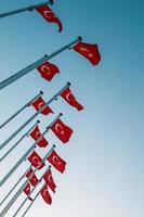Many national Turkish Flags on the masts against the blue sky. photo