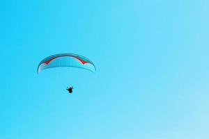 el parapente se eleva contra el cielo azul con espacio despejado. foto