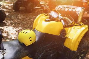 Yellow helmet on an ATV in the forest, in the mud. Wheels and elements of all-terrain vehicles in mud and clay. Active leisure, sports and tourism photo